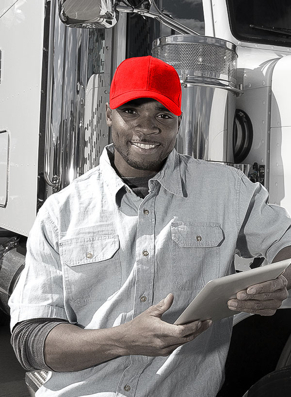 truck driver standing beside a transport truck, holding a tablet